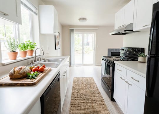 A kitchen with white cabinets and a black refrigerator.