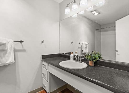 A bathroom with a sink, mirror, and a towel rack.