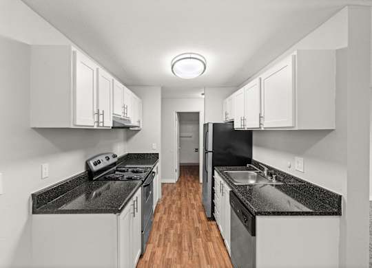 A modern kitchen with black countertops and white cabinets.