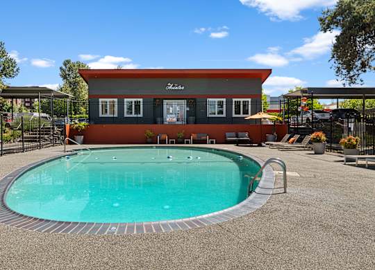 A pool in front of a house with a red and grey exterior.