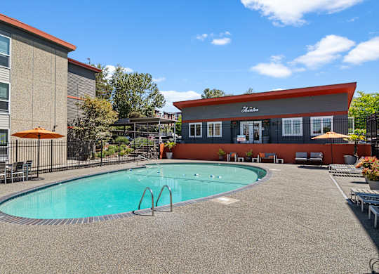 A pool area with a red building and a clear blue sky.