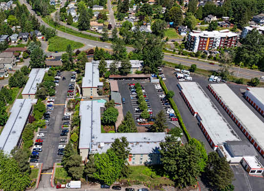 A parking lot is surrounded by buildings and trees.