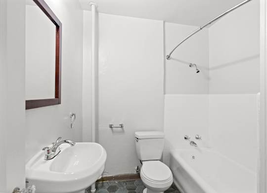 A white bathroom with a toilet, sink, and bathtub.