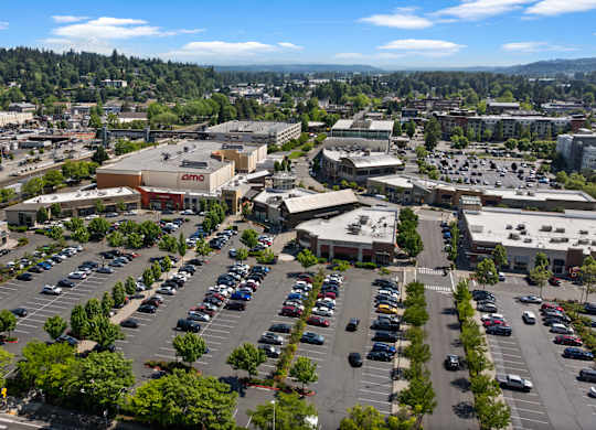 A parking lot with cars and a large building with a sign that says "Amazon" in the background.