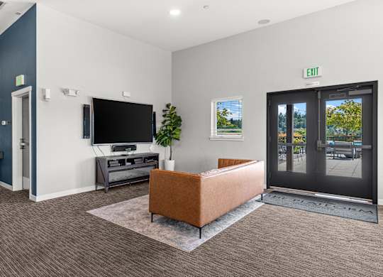 A room with a brown sofa and a television set.