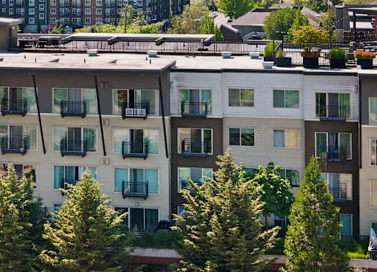 Apartment building with balconies and trees in front.