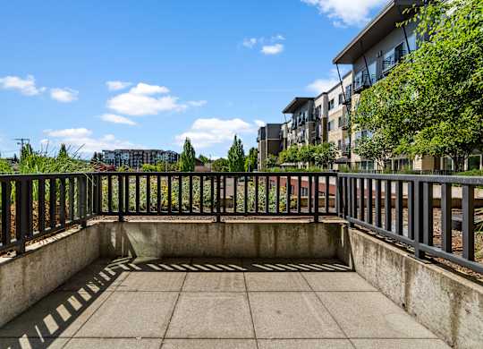 A sunny day at a courtyard with a fence and a building in the background.