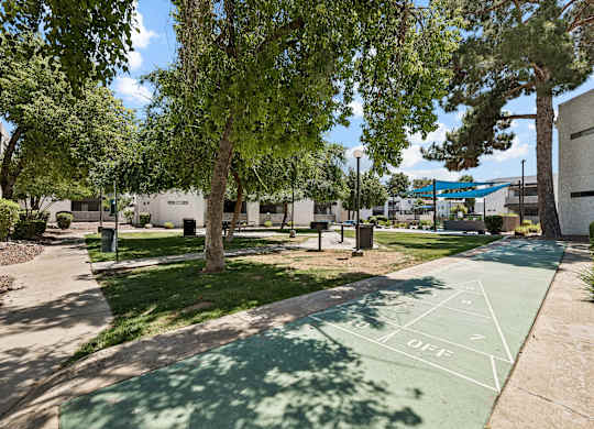 A basketball court in a park with a green surface and white lines.
