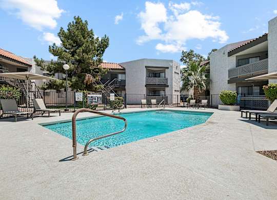 A swimming pool in a residential area surrounded by buildings and trees.