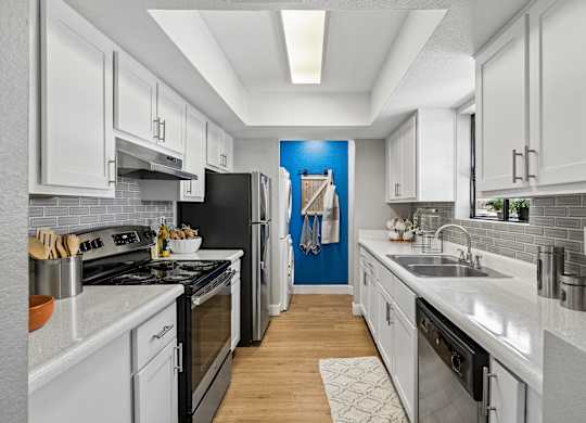A modern kitchen with white cabinets and a black stove top oven.