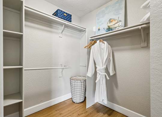 A white robe is hanging on a hanger in a white closet.