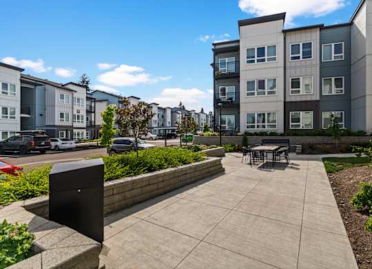 A modern apartment complex with a clean courtyard and a bench.