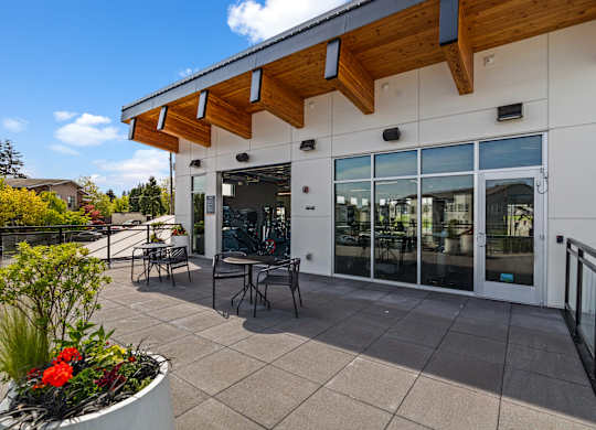 A white building with a wooden overhang and glass doors.