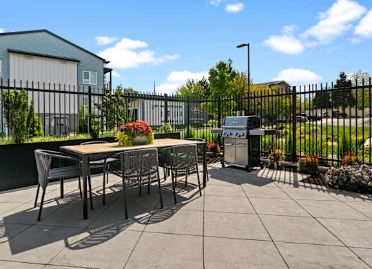 A patio with a table and chairs is surrounded by a black fence.
