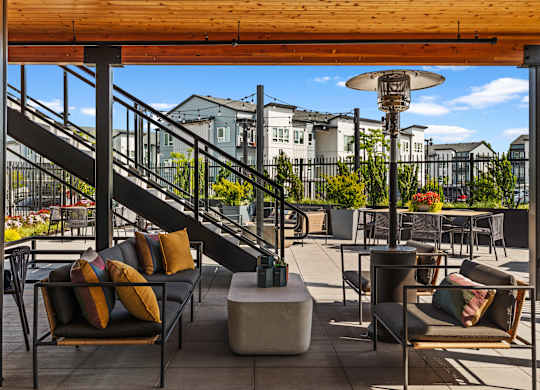 A patio with a black couch and a table with a lamp on it.