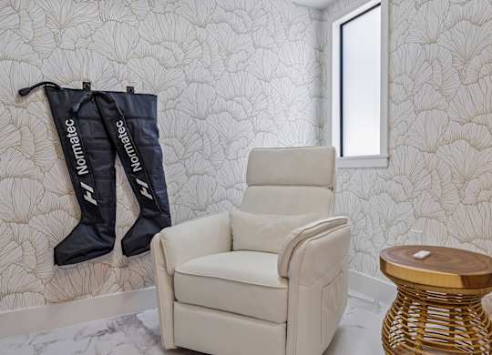 A chair and two boots are hanging on a wall.