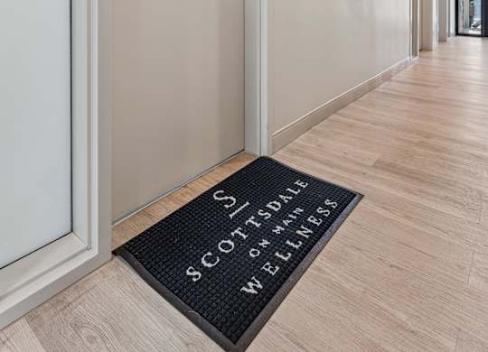 A hallway with a door and a doormat that says "Scottsdale Wells".