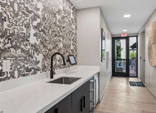 A modern kitchen with a white counter top and a black and white tiled wall.