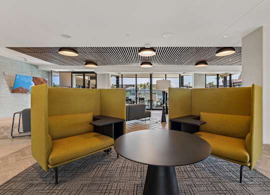 A modern office lounge with yellow sofas and a round table.