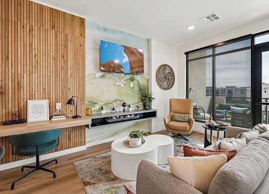 A modern living room with a green chair and a large painting on the wall.