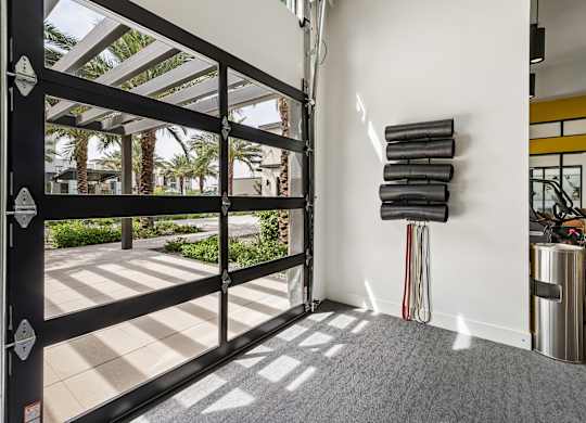 A black gate with a white stripe is open to a patio with palm trees.