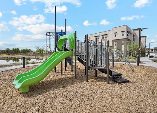 A green slide in a playground with a metal structure.