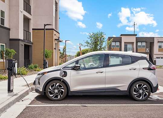 A silver car is parked and charging at an electric vehicle charging station.