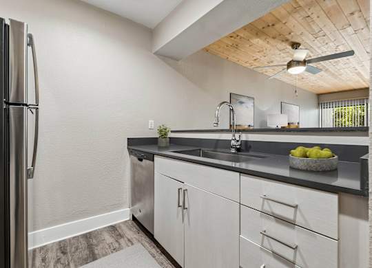 A modern kitchen with a black fridge and white cabinets.