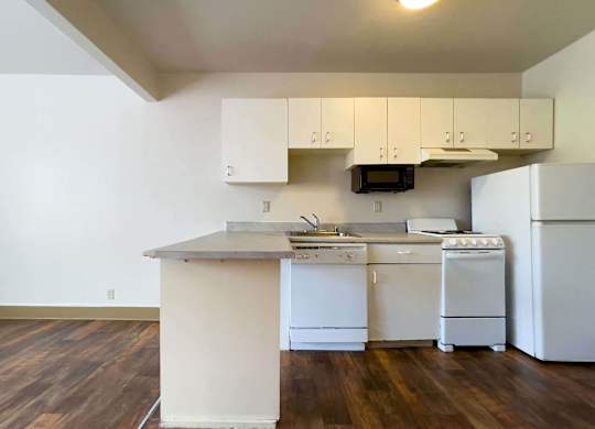 A kitchen with white appliances and wooden floors. at Zindorf, Seattle, 98104