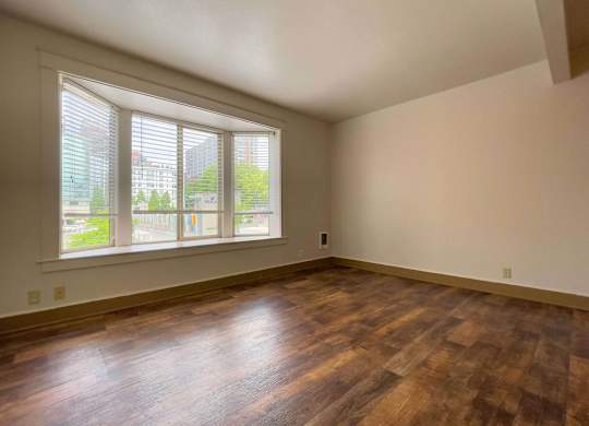 A room with wooden floors and a large window with blinds. at Zindorf, Seattle, WA