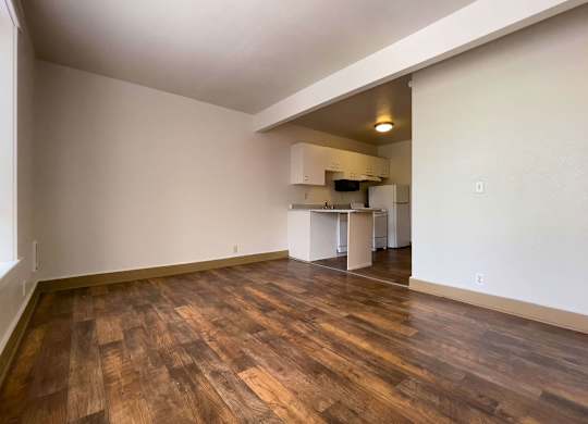 A room with wooden flooring and a kitchen area in the background. at Zindorf, Seattle, WA, 98104