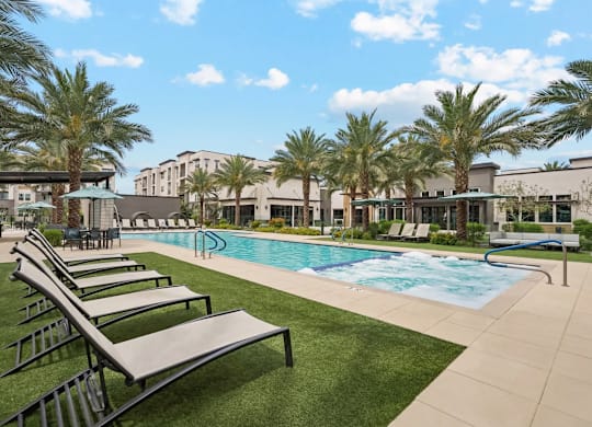A pool surrounded by palm trees and lounge chairs.