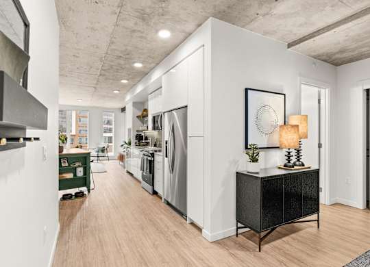 A modern kitchen with white walls and wooden floors.