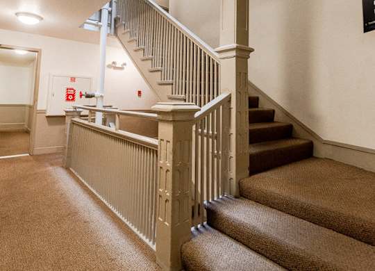 A staircase with a carpeted runner and a wooden banister. at Zindorf, Seattle, WA
