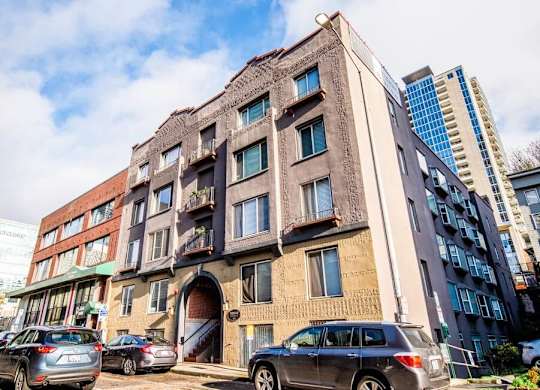 A large, old building with a lot of windows is in front of a modern building. at Zindorf, Seattle, Washington