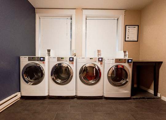 Three front load washing machines in a laundry room. at Zindorf, Seattle, Washington