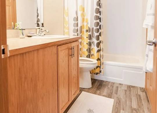 A bathroom with wooden cabinets and a white shower curtain. at The Retreat, Sumner, 98390