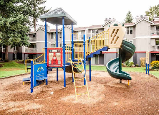 A playground with a green slide and a blue and yellow play structure. at Notch 8, Tacoma, Washington