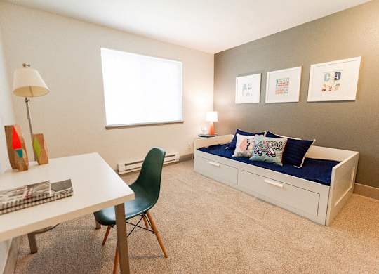 A room with a desk, chair, and bed.