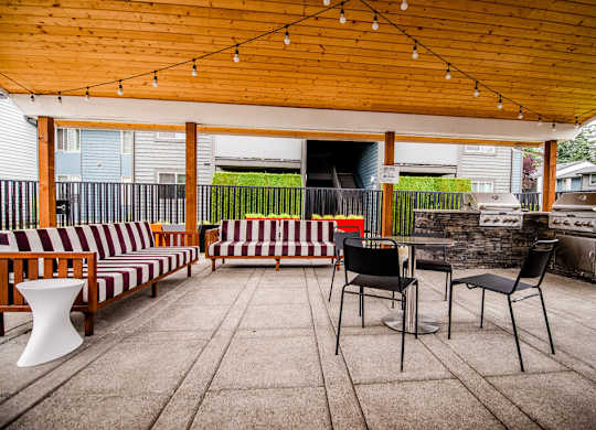 A patio with a striped couch and a table with chairs.