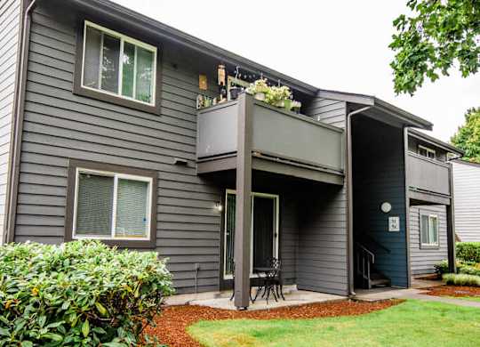 A grey house with a green lawn in front.
