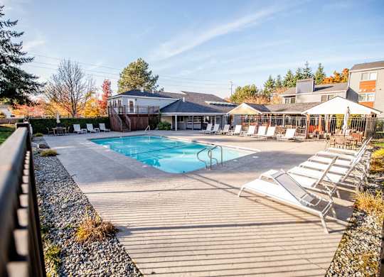 A pool area with sun loungers and a building in the background. at Northpoint Apartments, Tacoma, WA, 98407