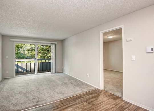 A room with a carpeted floor and a sliding glass door leading outside. at The Lakes at Fife, Fife, WA