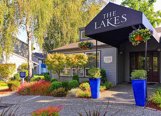 The Lakes building has a black awning and is surrounded by blue planters. at The Lakes at Fife, Fife, WA