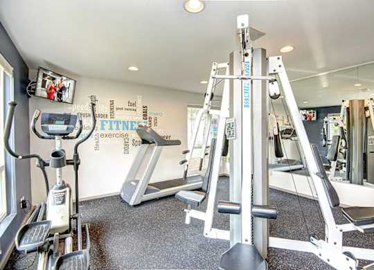 A gym with a treadmill, elliptical trainer and a leg press machine. at The Lakes at Fife, Fife, WA