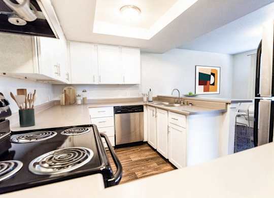 A modern kitchen with a stove top oven and white cabinets.