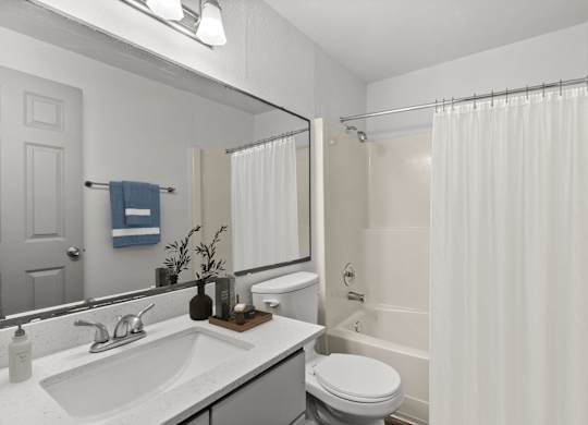 A white bathroom with a toilet, sink, and shower.