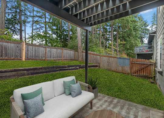 A white couch with two green pillows sits on a wooden deck.