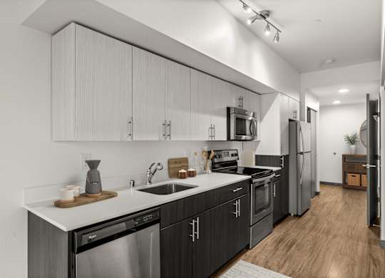 A modern kitchen with dark wood cabinets and stainless steel appliances.