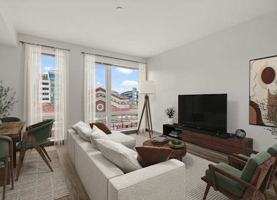 A living room with a white couch, a wooden coffee table, and a large window with a view of the city.